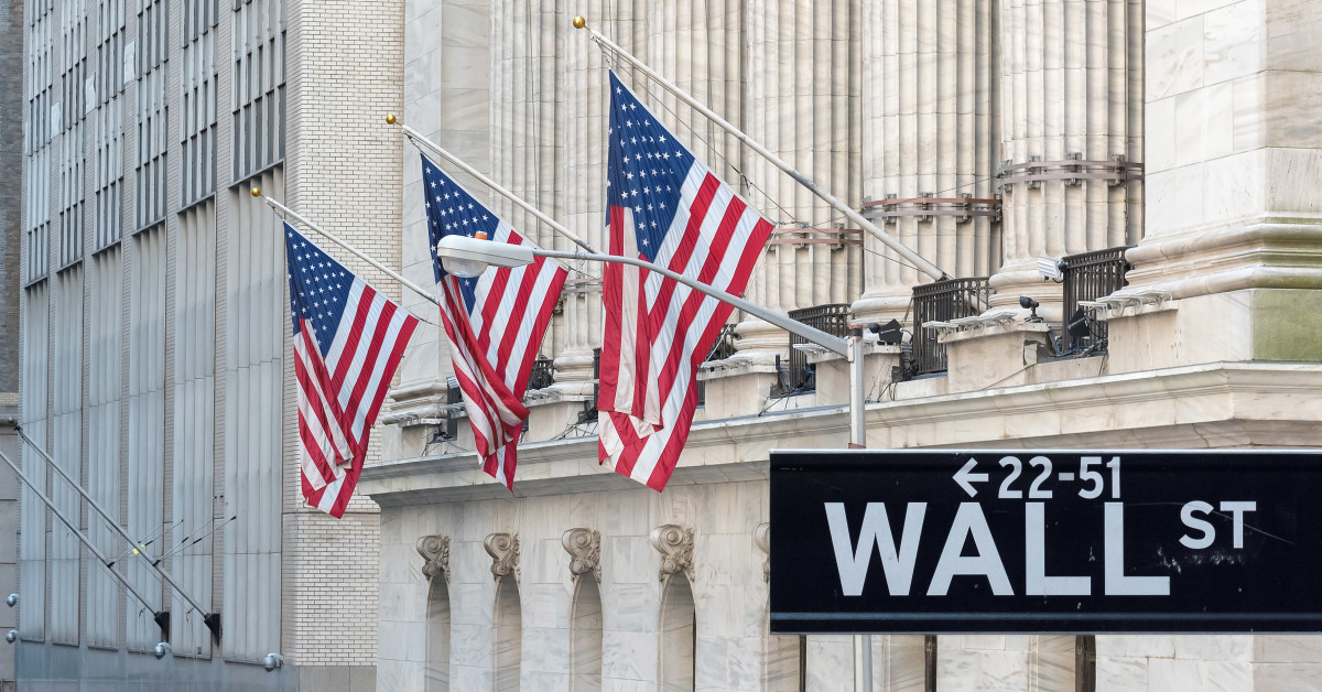 New York Stock Exchange building on Wall Street with US flag and market charts background